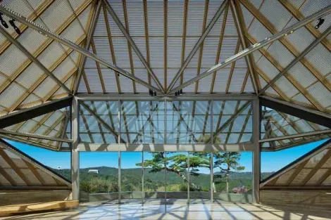 L'edificio del Museo Miho e la sua grande vetrata si affacciano su un paesaggio di pini e aceri.